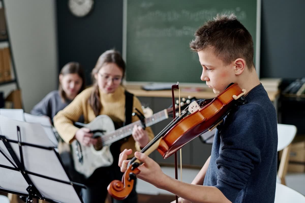 Middle school students practicing violin and guitar in a music classroom
